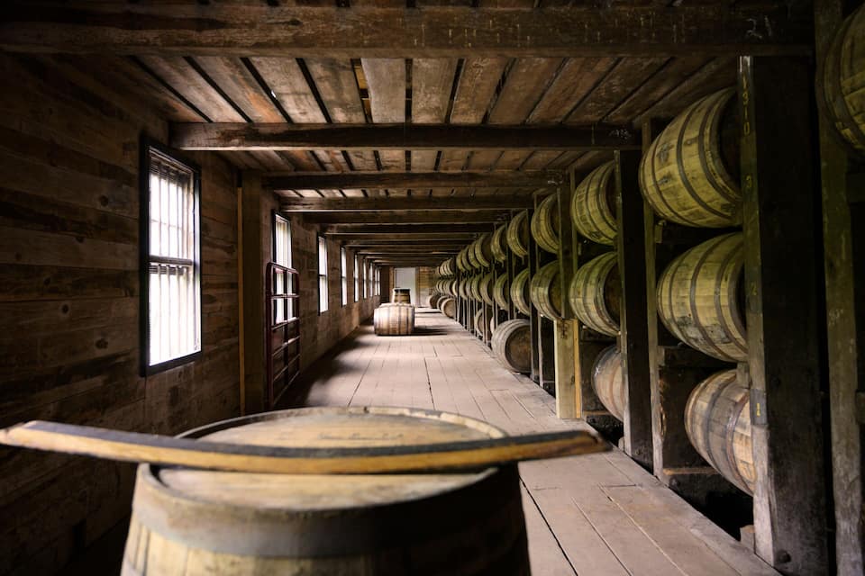A wooden barrel room with barrels lined up on both sides and a wooden floor.