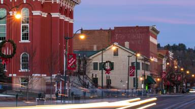 A historic building with a clock tower, red brick facade, and Christmas decorations.