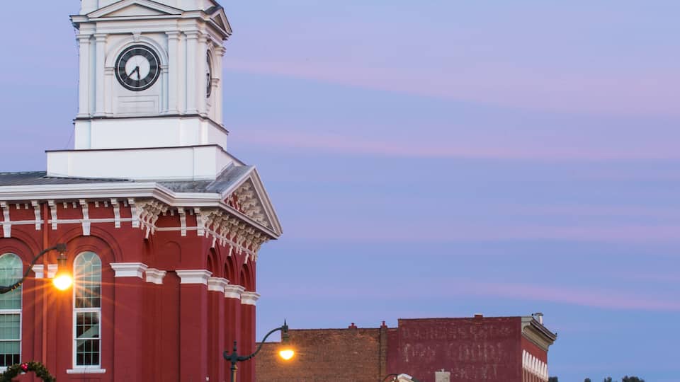A historic building with a clock tower, red brick facade, and Christmas decorations.