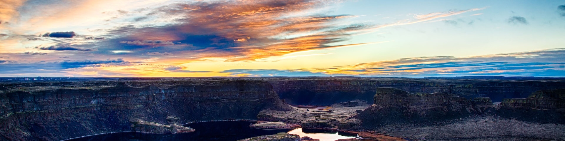 A canyon with reflective water bodies and a sunset sky.
