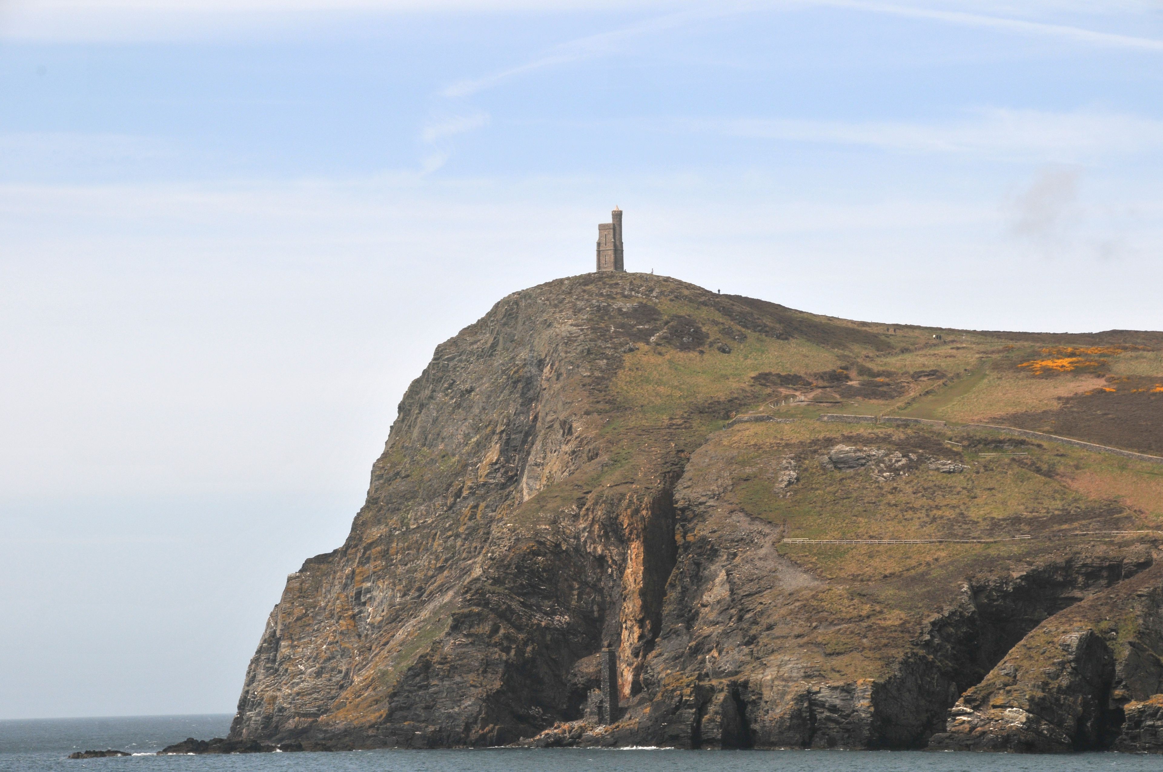 A rugged cliff with a tower on top, overlooking the sea.