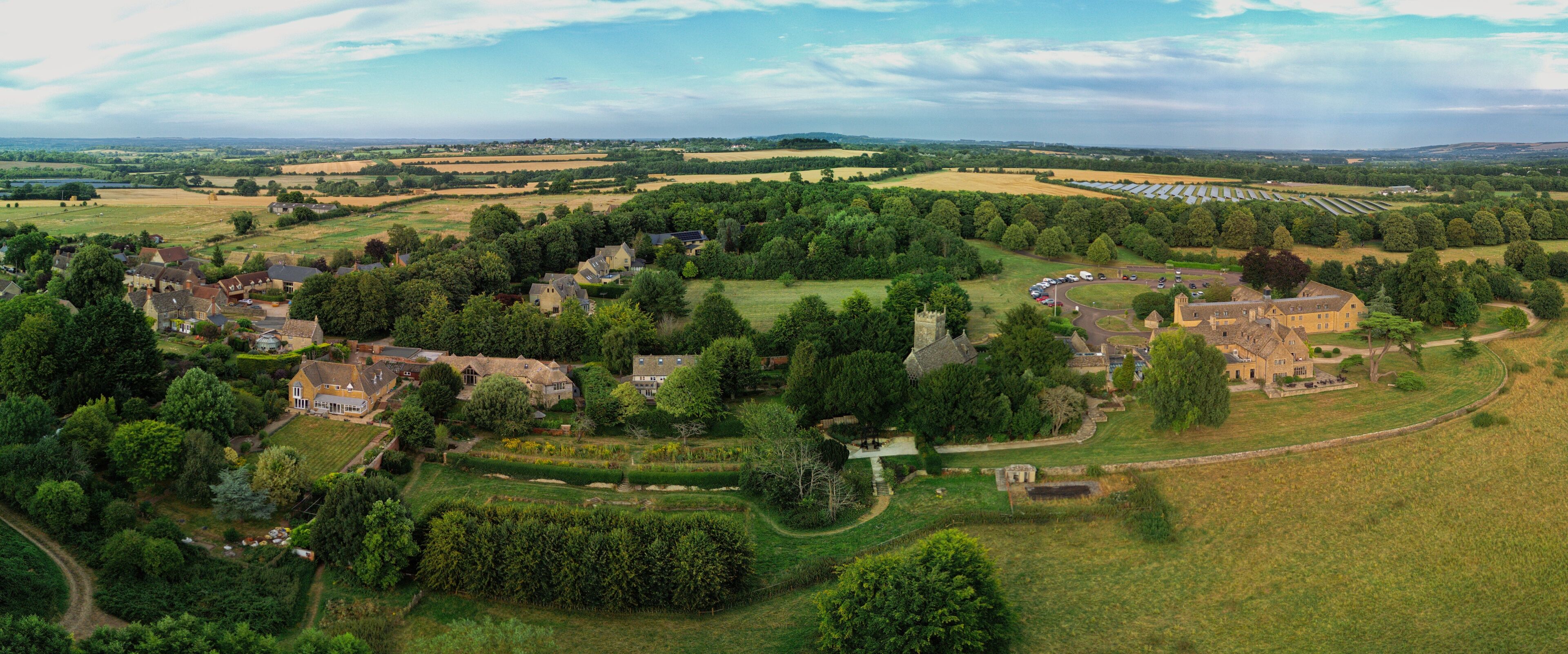 A rural landscape with a historic estate, rolling fields, and scattered trees.