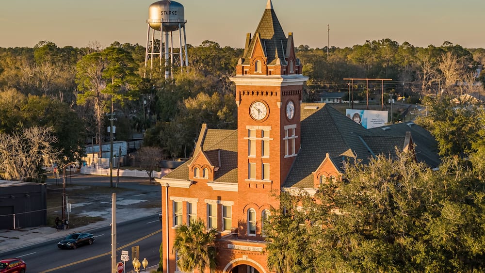 A historic building with a clock tower, a water tower, and a street with cars.