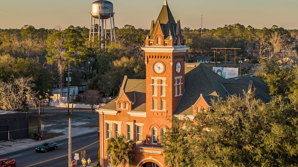 A historic building with a clock tower, a water tower, and a street with cars.