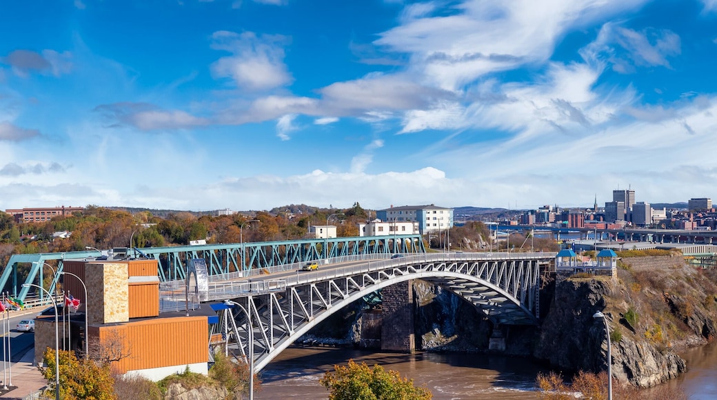 Un pont enjambant une rivière, avec la silhouette d’une ville en arrière-plan.