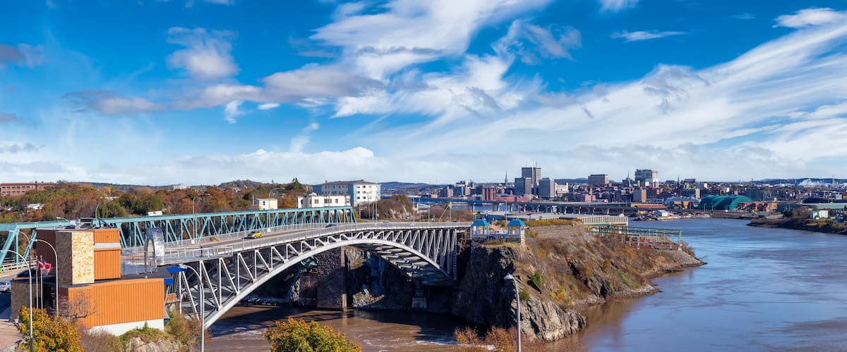 Un pont enjambant une rivière, avec la silhouette d’une ville en arrière-plan.