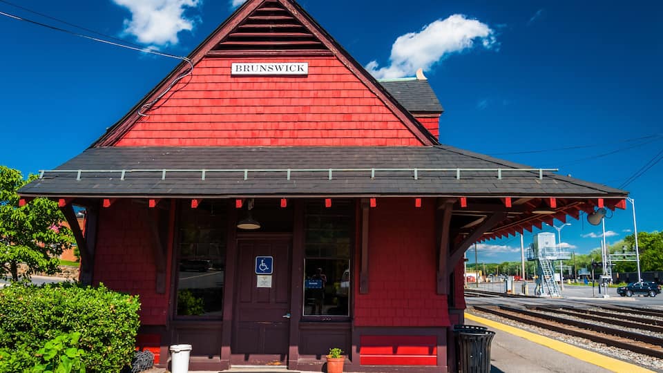 A red train station named Brunswick with a clear blue sky and a train track.