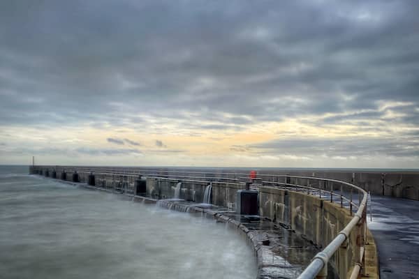 The wall protecting the harbour. Waves were breaking over the wall but still there was someone fishing on the end