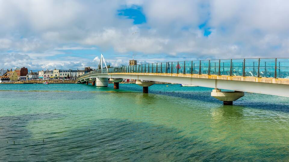 A modern bridge over a body of water with clear skies.