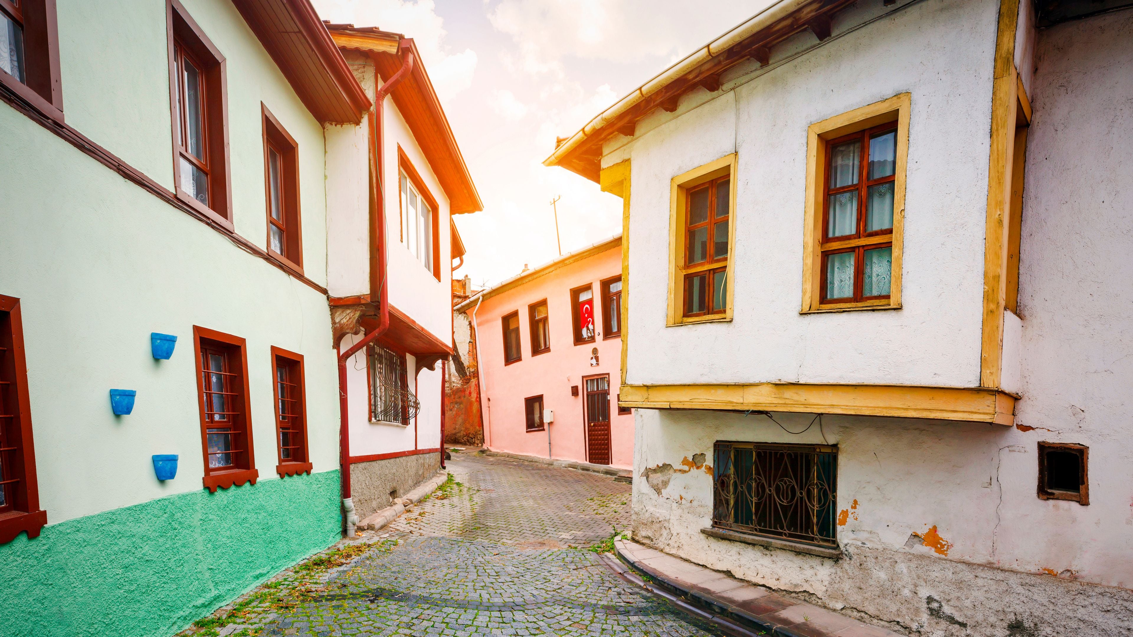 Une ruelle étroite pavée, bordée de bâtiments aux couleurs vives et à l’architecture traditionnelle.