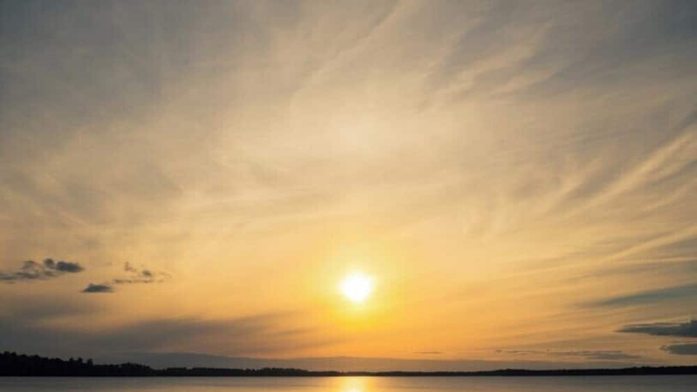 Eine Holzsteige, die sich in ruhiges Wasser bei Sonnenuntergang erstreckt.