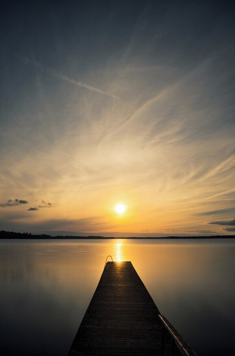 A wooden pier extending into calm water during sunset.