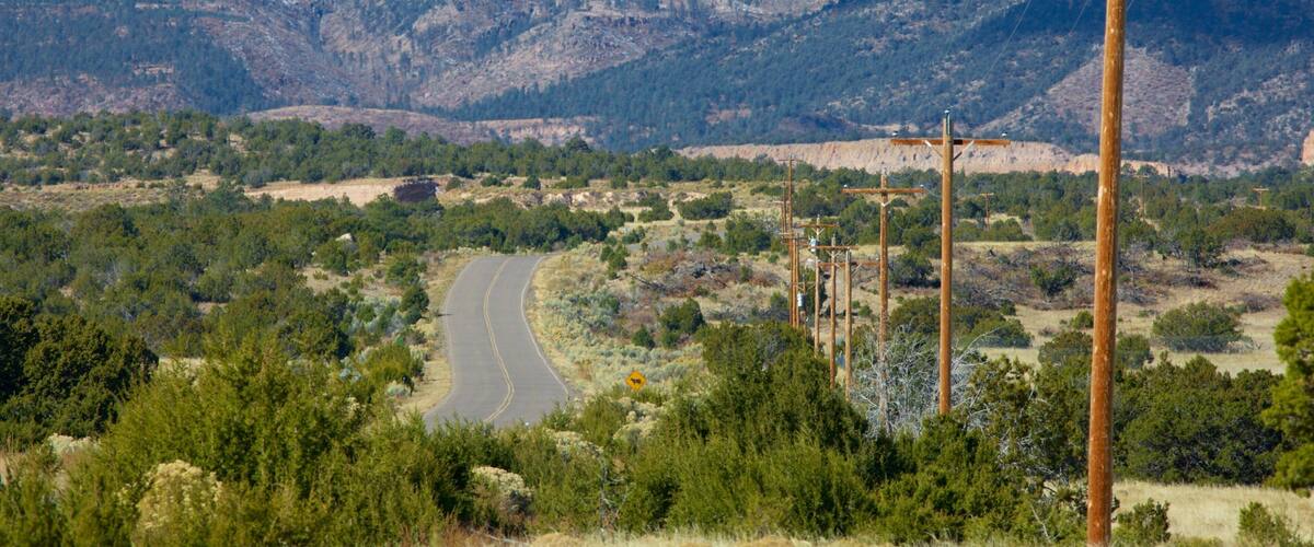 A winding road through a mountainous landscape with sparse vegetation and utility poles.