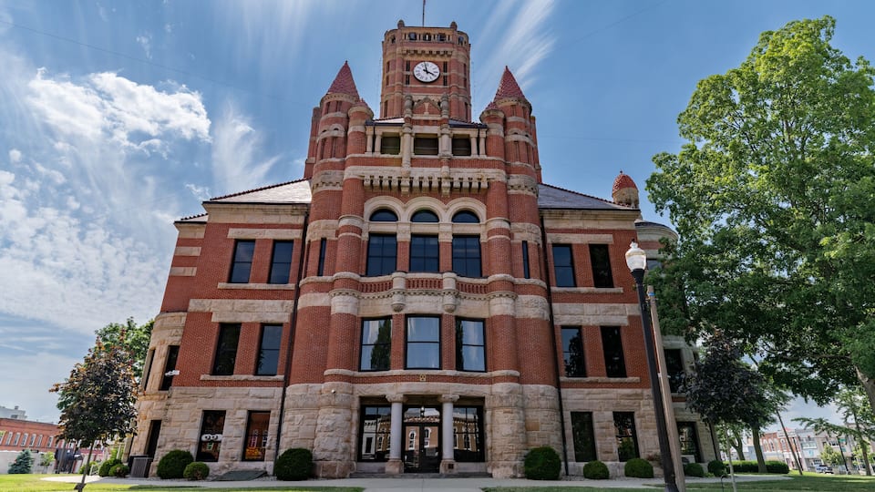 A large brick building with a clock tower, surrounded by well-maintained lawns and trees.