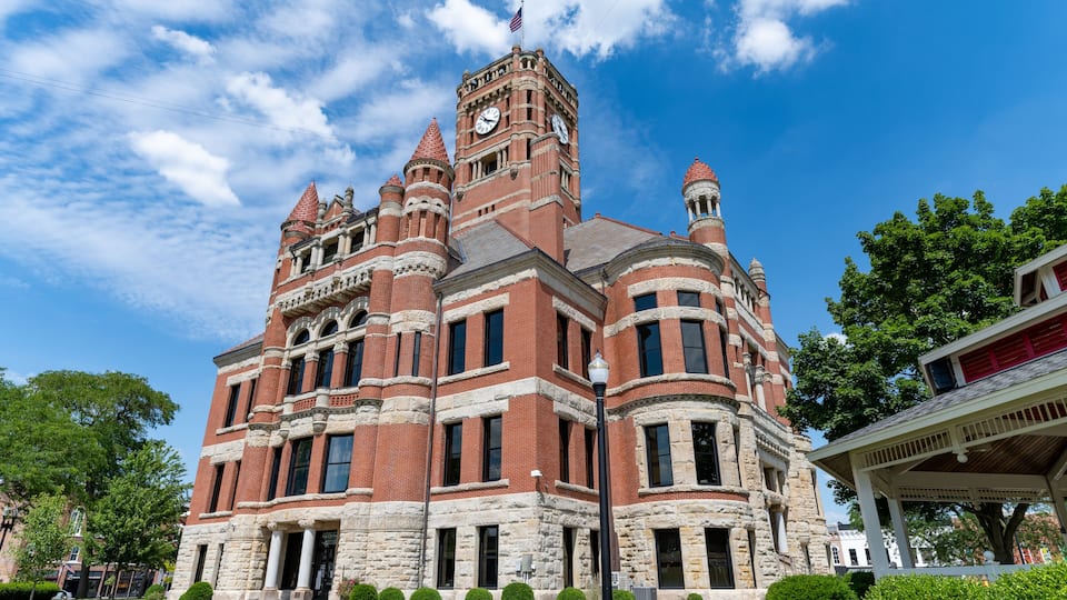 A historic building with a clock tower, surrounded by well-maintained lawns and trees.