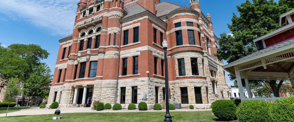 A historic building with a clock tower, surrounded by well-maintained lawns and trees.