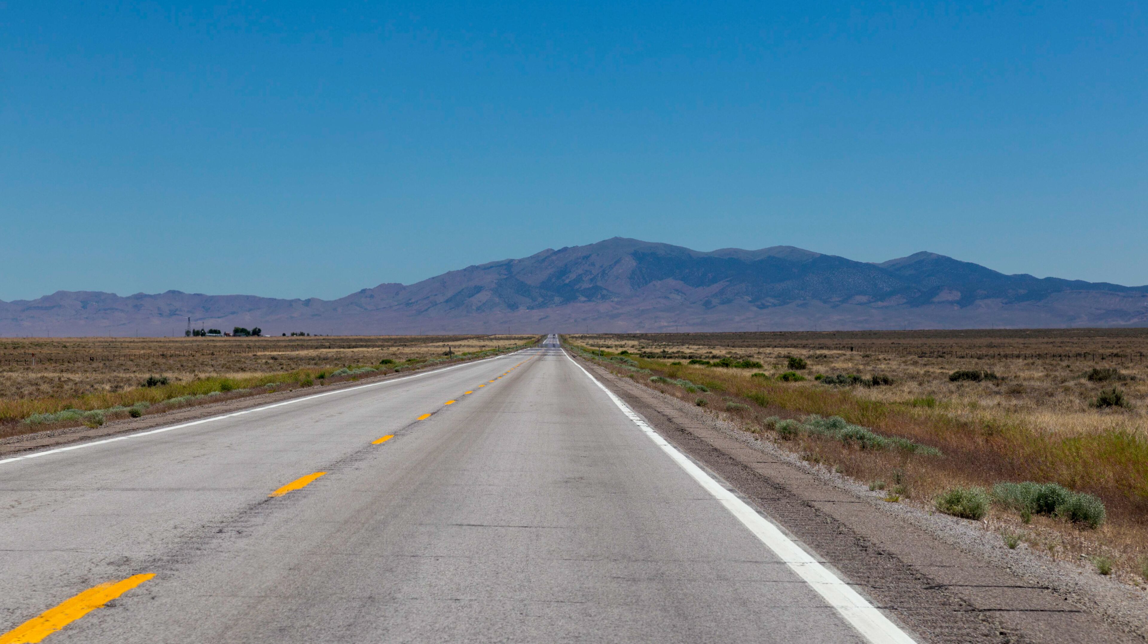 A straight road with mountains in the distance.