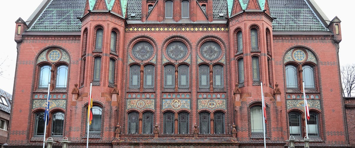 A large red brick building with ornate windows and a central clock.