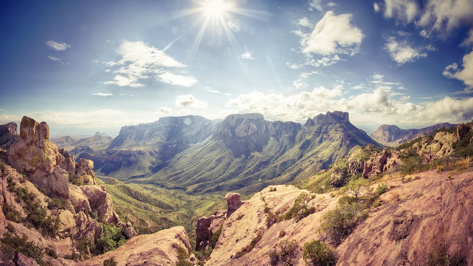 A mountainous landscape with rocky outcrops and green vegetation under a clear sky.
