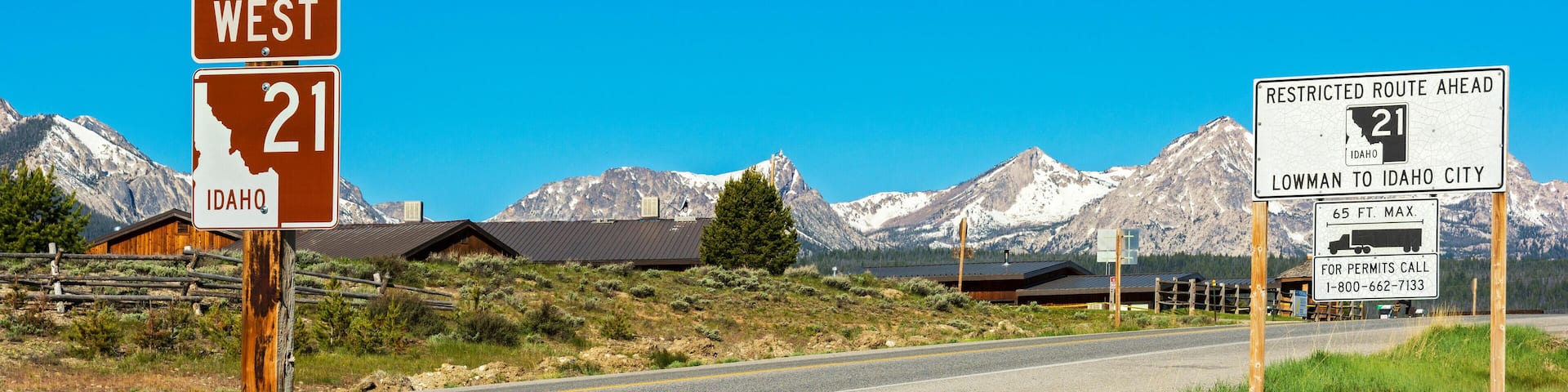 A scenic route sign for Ponderosa Pine Scenic Byway, West 21 in Idaho, with a mountain backdrop.
