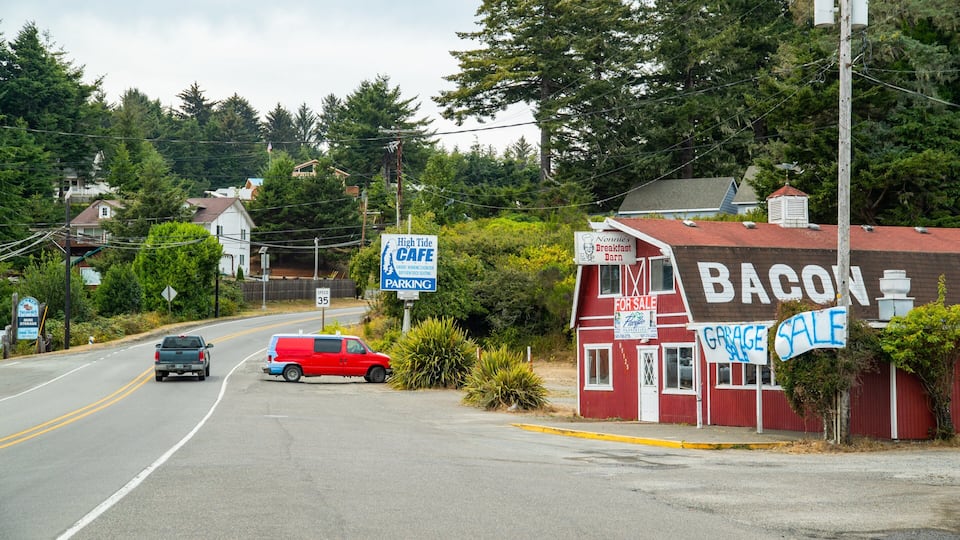 A road with a speed limit sign, a red van, and a building with a 'Bacon' sign.