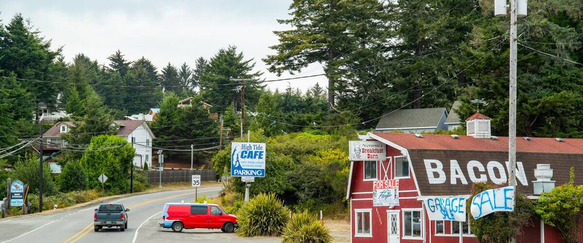 A road with a speed limit sign, a red van, and a building with a 'Bacon' sign.
