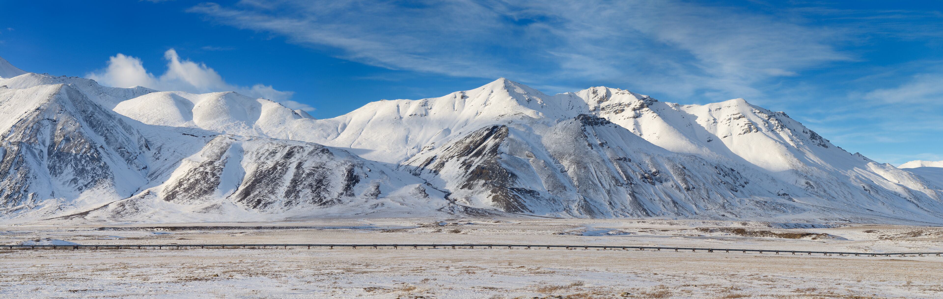 Panorama of the Alyeska crude oil pipeline running through the snowy Brooks Range mountains Alaska