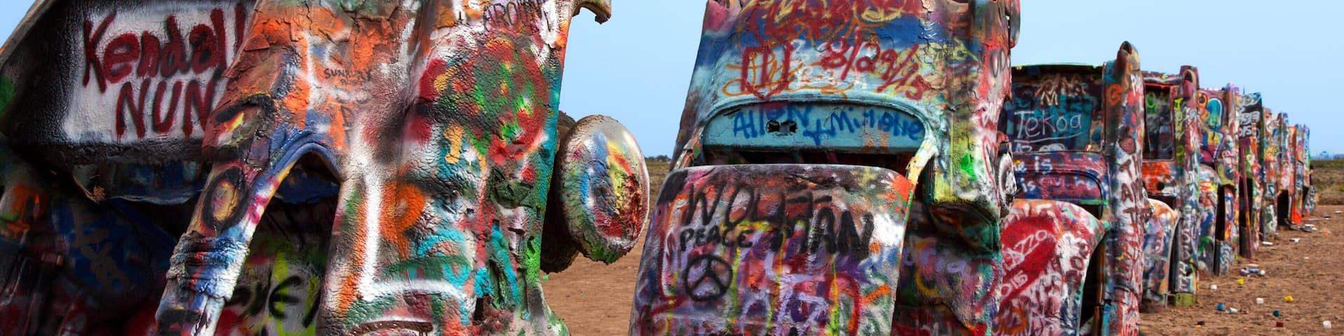 A row of colorful, graffiti-covered sculptures in an outdoor setting.