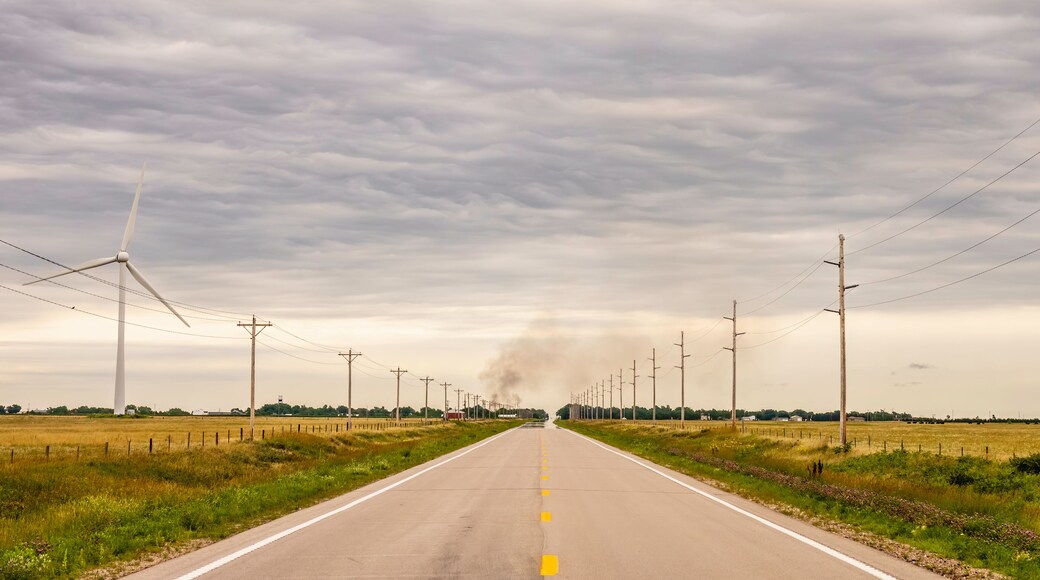 Perspective of Nebraska Highway 12, also known as Outlaw Trail Scenic Byway, with wind turbine (left), smoke rising from a house fire in the town of Springview, and mirage of water across pavement; Sh