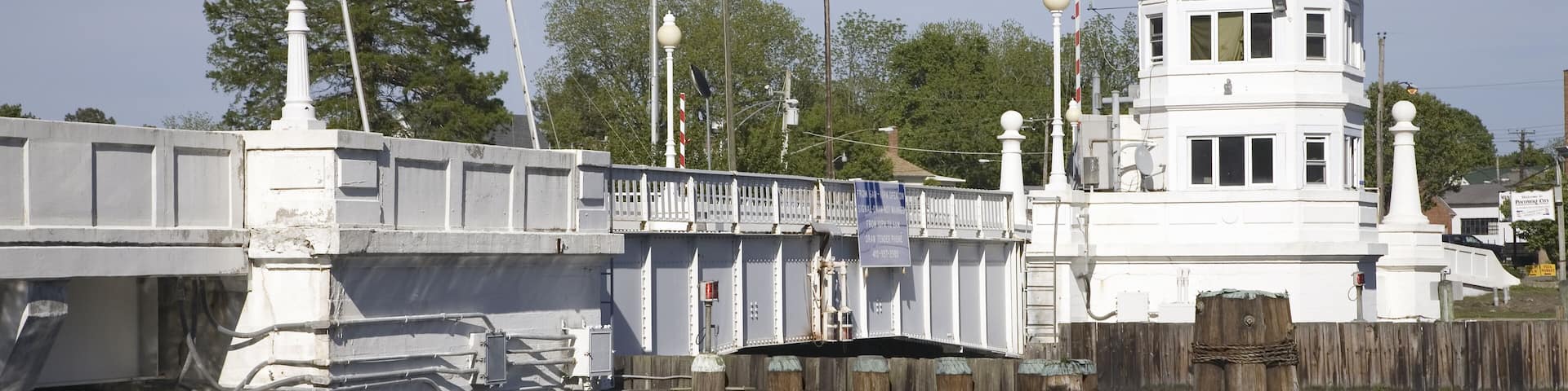 A white tower with a rounded roof, a bridge with a white railing, and an American flag.