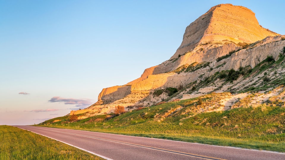 A road leading to a large hill with a flat top.
