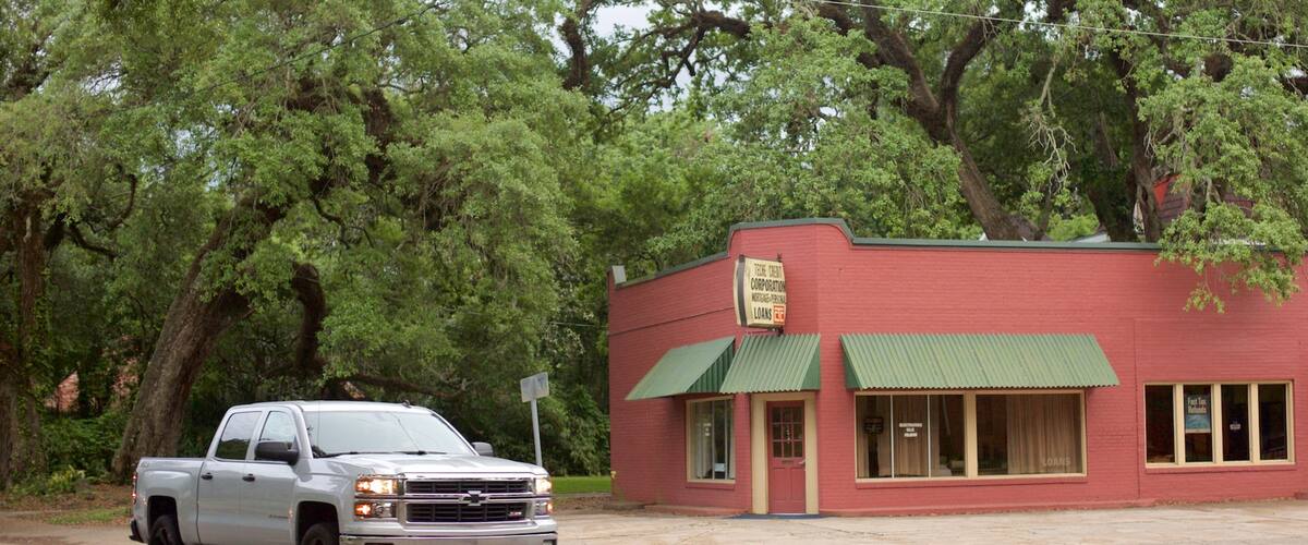 A white pickup truck parked in front of a red building with green awnings, labeled as a mortgage company.