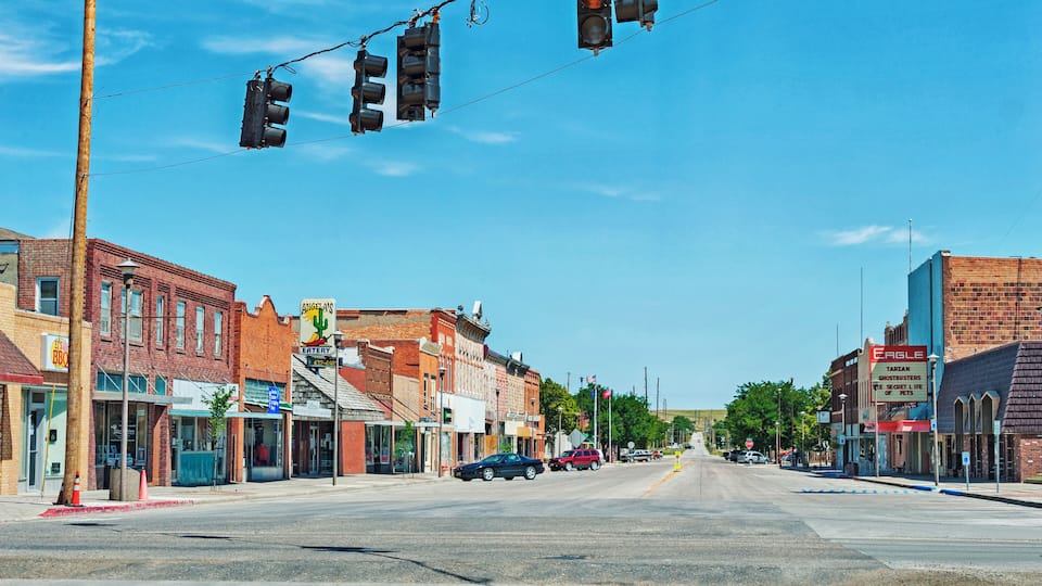 A street with buildings, traffic lights, and cars.