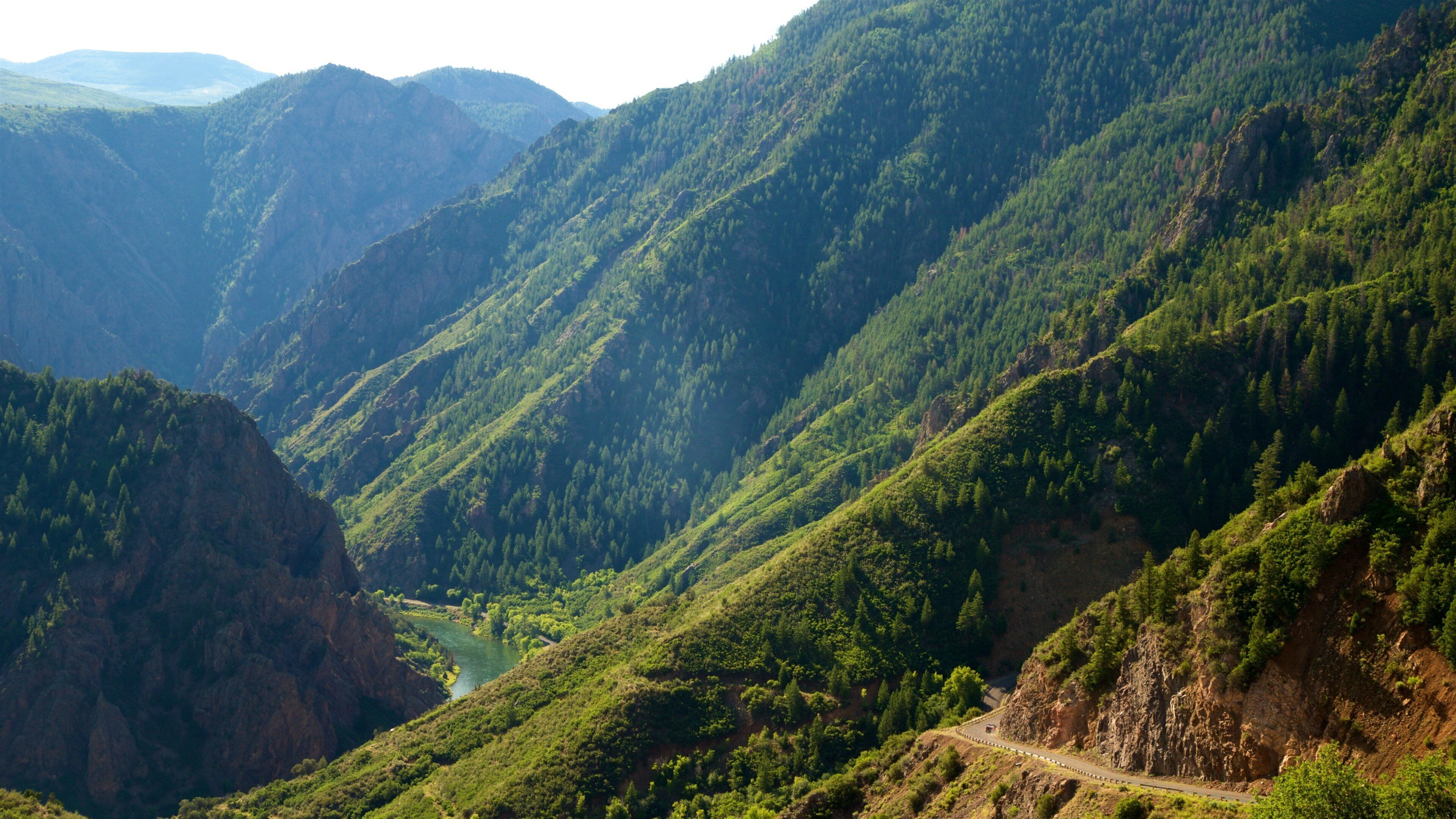 A mountainous landscape with a winding road and a river.