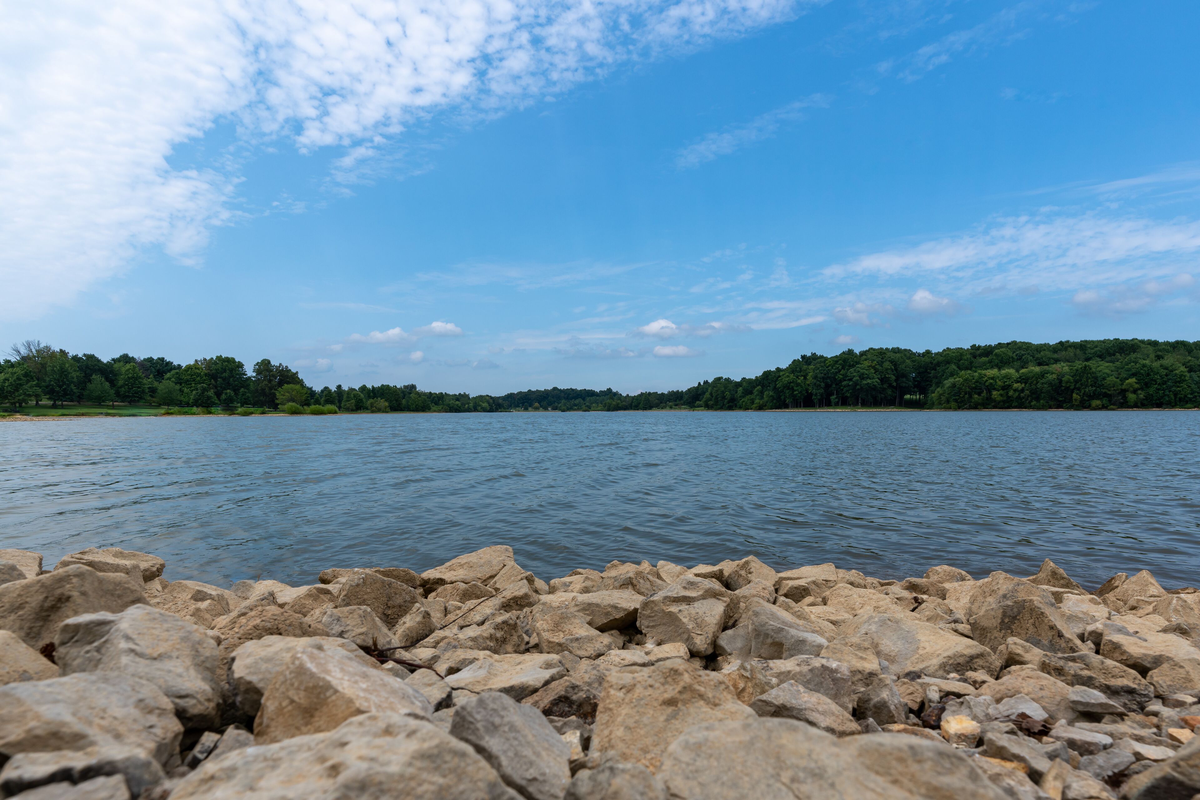 Gorgeous sunny summer day at Freeman Lake in Elizabethtown, KY.  Composed with rocks in the foreground and a blue sky with some clouds in the sky.