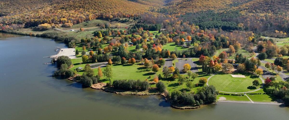 A lakeside resort with autumn foliage, a marina, and rolling hills.