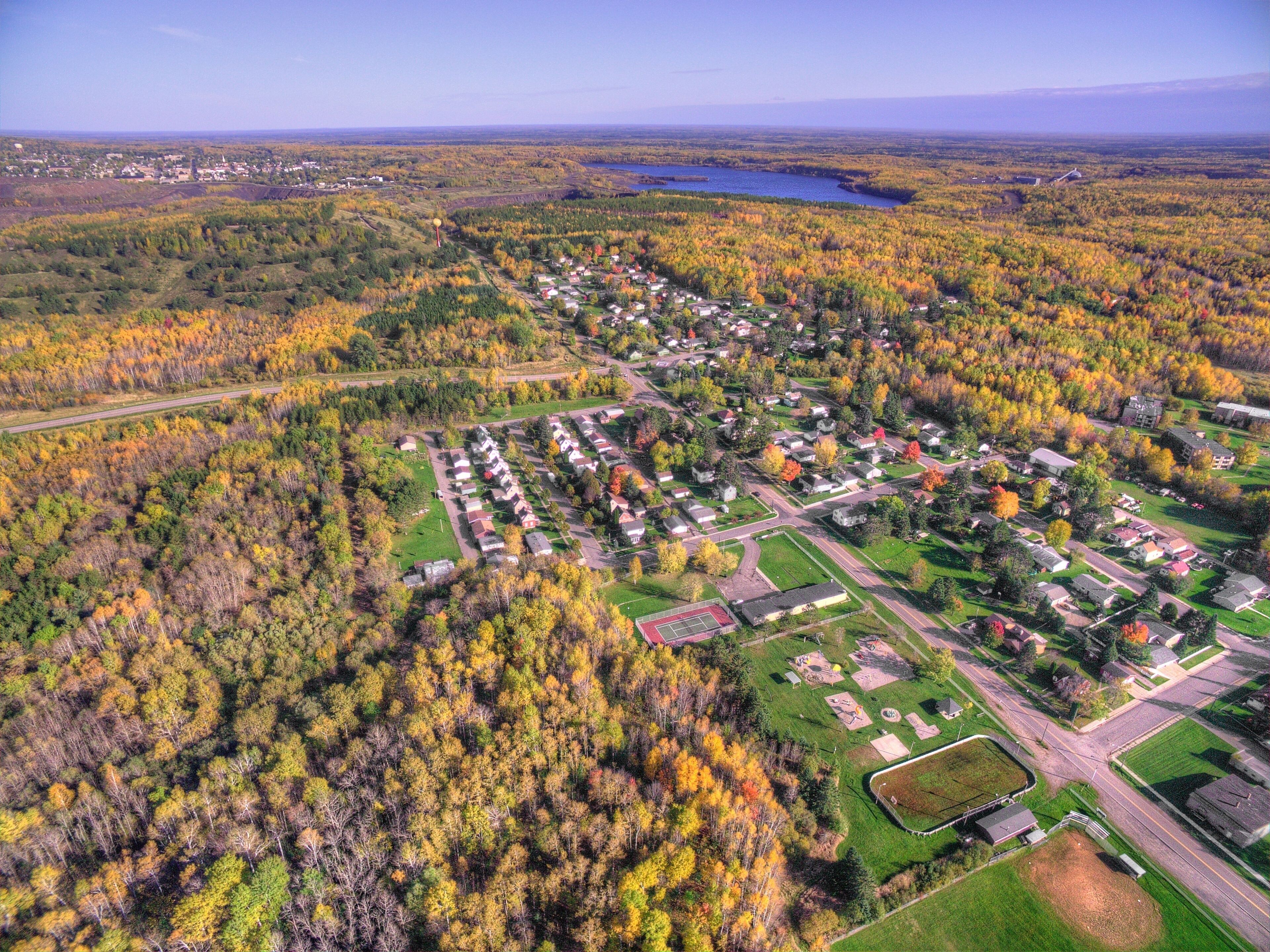 An aerial view of a residential area with houses, roads, and a lake in the background.