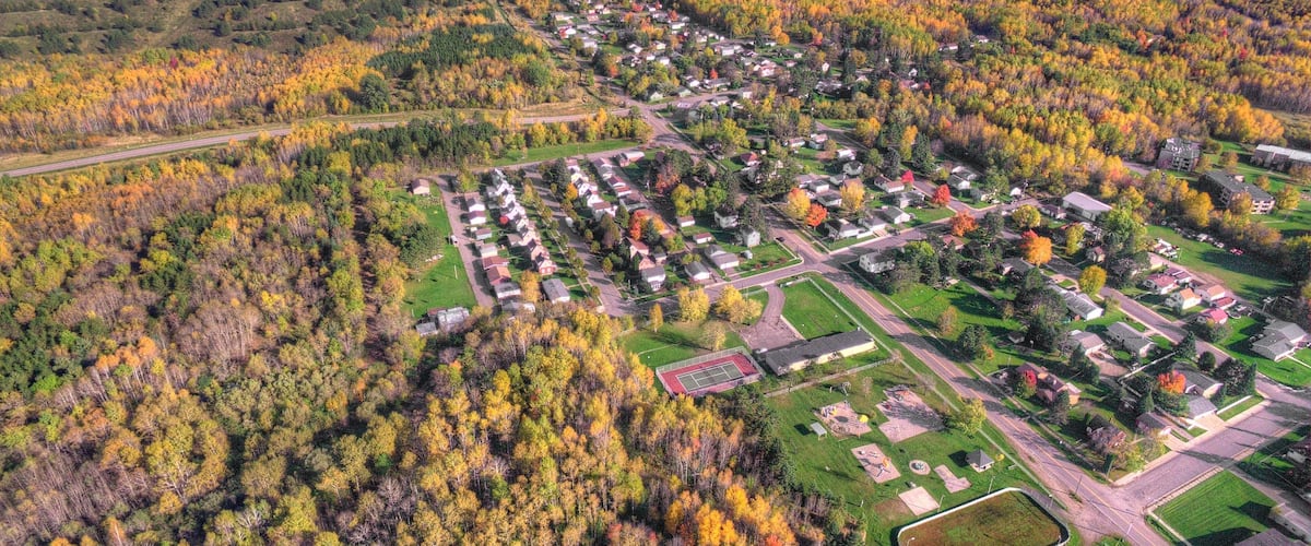 An aerial view of a residential area with houses, roads, and a lake in the background.