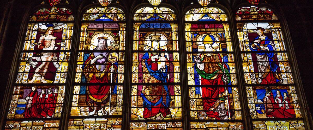A stained glass window with religious figures and intricate designs.