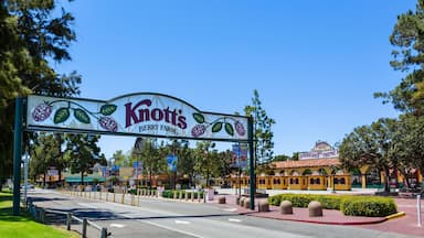 A sign for Knott's Berry Farm with a clear blue sky and a yellow building in the background.