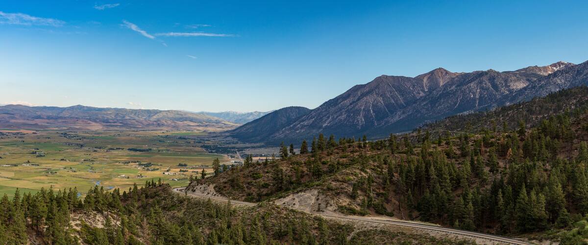 A mountainous landscape with a winding road, dense forest, and distant valleys.