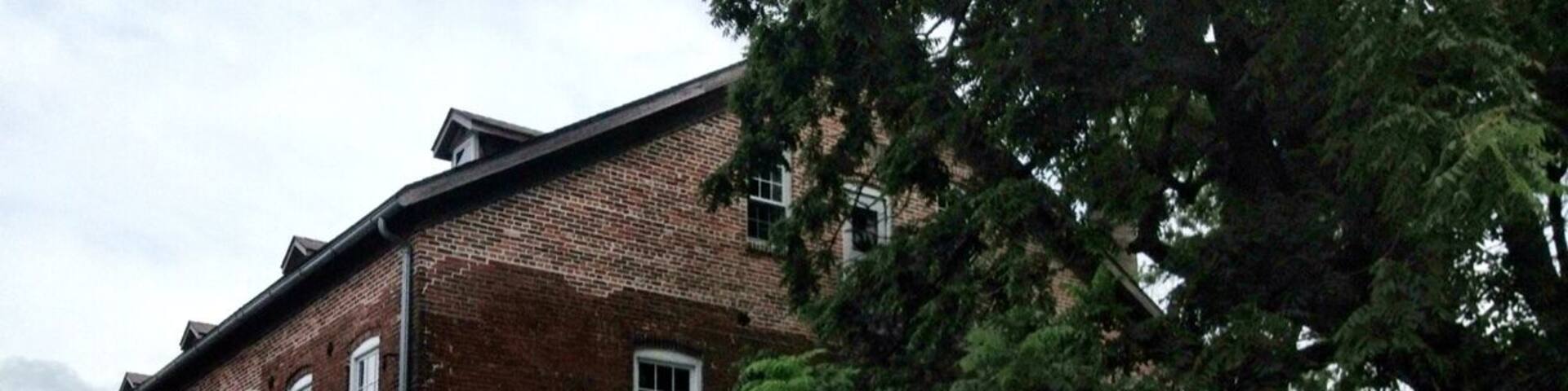 A brick building with a sign that reads "Amana Woolen Mill, Operating since 1857."
