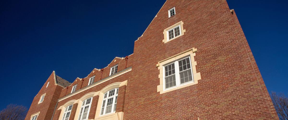 A red brick building with a stone staircase, large windows, and a clear blue sky.