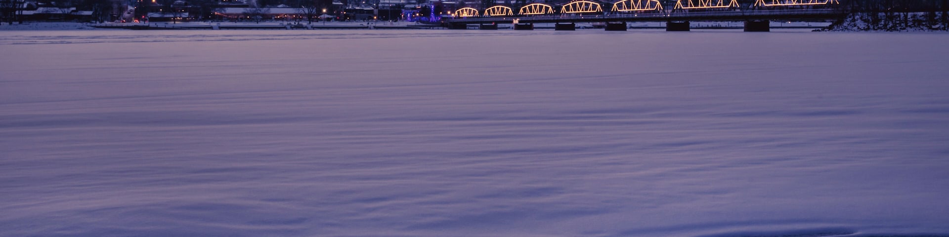 A frozen river with a bridge in the background.