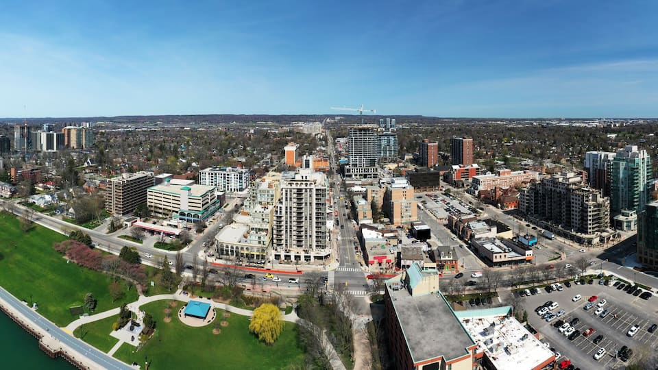 An aerial view of a coastal city with a marina, high-rise buildings, and a large park area.