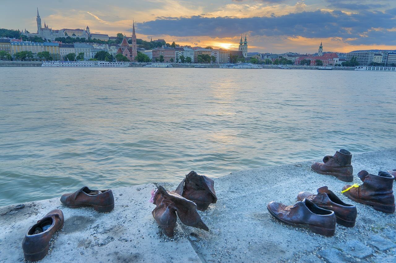 Un río con barcos, un atardecer y un paisaje urbano con edificios históricos.