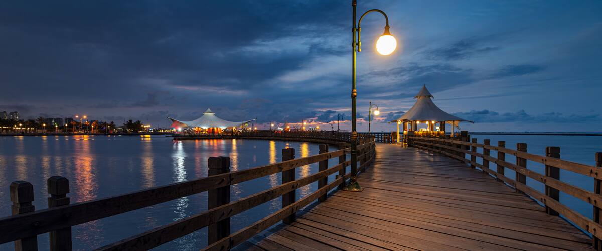 Serene Blue Hour View of the Illuminated Wooden Love Bridge at Ancol Beach, Jakarta