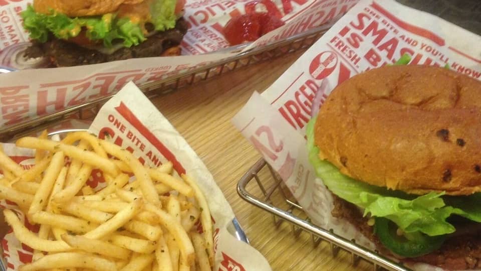 Two burgers and a container of fries on a table.
