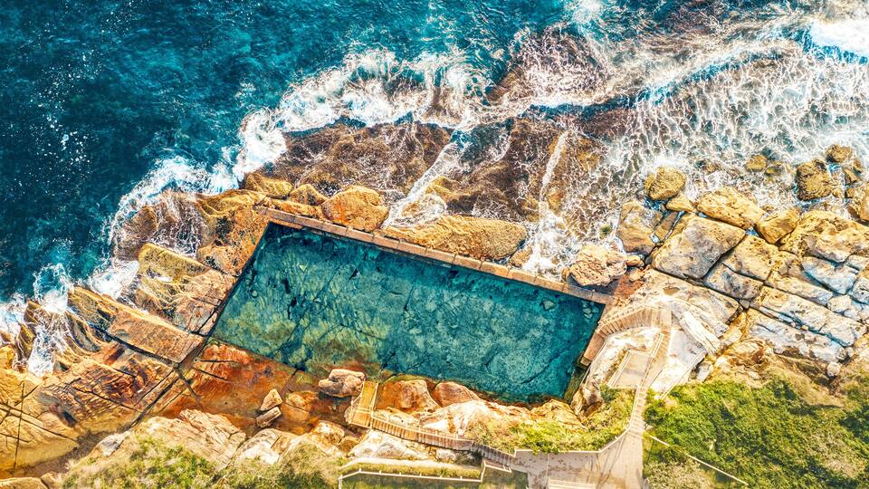 A rocky coastline with a swimming pool.