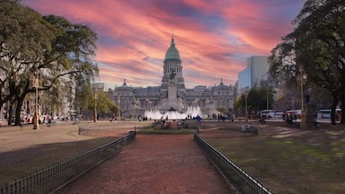 Un parque con una fuente, un edificio grande con cúpula y árboles.